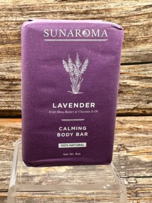 Lavender calming body bar placed on a glass stand against a wooden wall