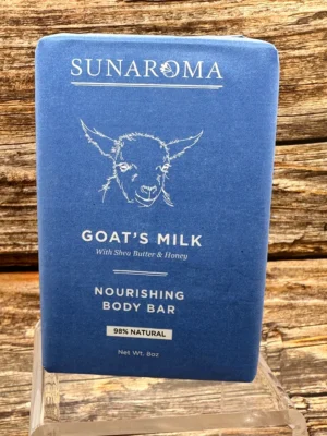 Blue bar of goat's milk nourishing body bar placed on a wooden surface