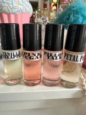 Four bottles of perfume sitting on top of a white shelf